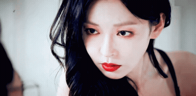 Woman With Long Black Hair And Red Lips Looking In Mirror GIF