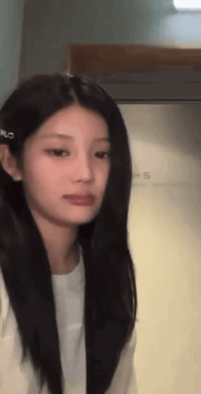 Woman With Long Black Hair And White Shirt Standing In Front Of Door GIF