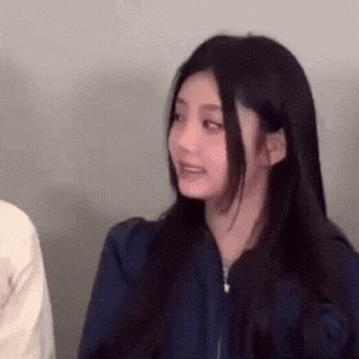 Woman With Long Black Hair In Blue Jacket Looking At Camera GIF