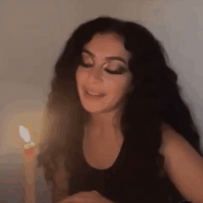 Woman With Long Black Hair Sitting By Candle GIF