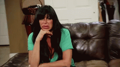 Woman With Long Black Hair Sitting On Leather Couch Hand On Chin GIF