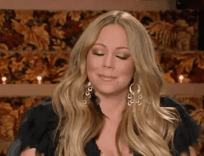 Woman With Long Blonde Hair And Earrings Sitting By Candles GIF