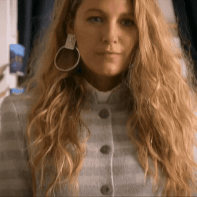 Woman With Long Blonde Hair and Hoop Earrings in Striped Jacket