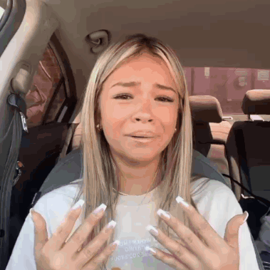 Woman With Long Blonde Hair And White Nails Sitting In Car Hands Outstretched GIF