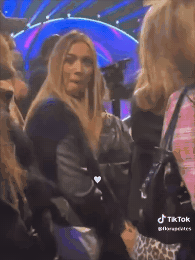 Woman With Long Blonde Hair Sitting In Crowd TikTok Watermark GIF