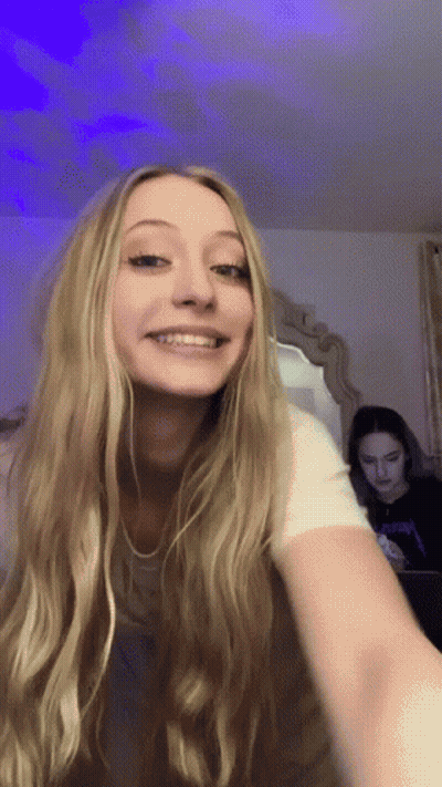 Woman With Long Blonde Hair Smiling in Mirror While Another Woman Looks On