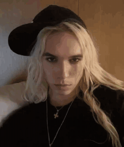 Woman With Long Blonde Hair Wearing Hat And Necklace GIF