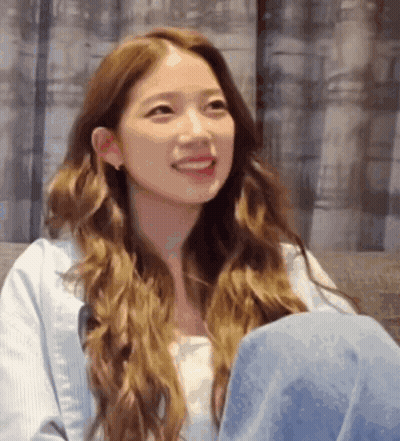 Woman With Long Brown Hair Smiling On Couch GIF