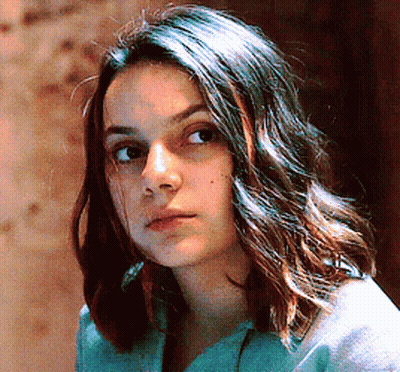 Woman With Long Dark Hair In Blue Shirt Looking At Camera GIF