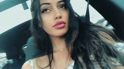 Woman With Long Dark Hair Sitting In Car Looking At Camera GIF