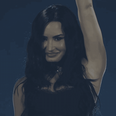 Woman With Long Dark Hair Smiling Hand In Air GIF