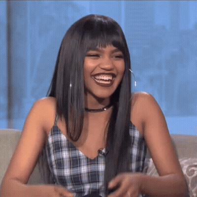 Woman With Long Hair And Bangs Smiling On Couch GIF