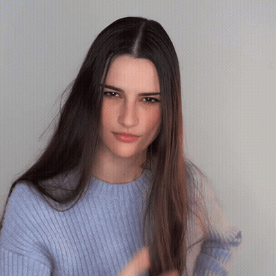 Woman With Long Hair And Blue Sweater Looking At Camera GIF