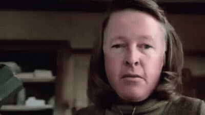 Woman With Long Hair And Necklace Looking At Camera In Kitchen GIF