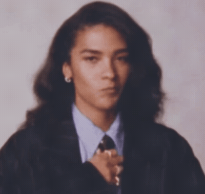 Woman With Long Hair In Suit And Tie Looking At Camera GIF