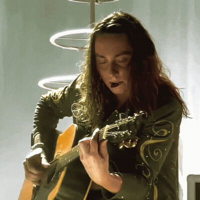 Woman With Long Hair Playing Guitar With Swirl Jacket GIF