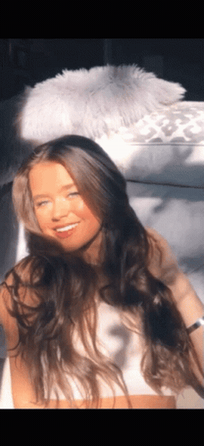Woman With Long Hair Sitting On White Couch GIF