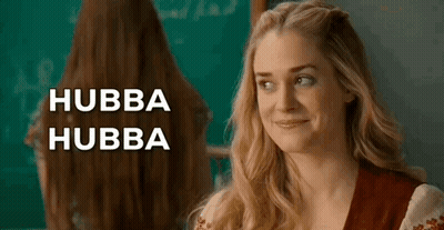 Woman With Long Hair Smiling In Front Of Blackboard And Mirror GIF
