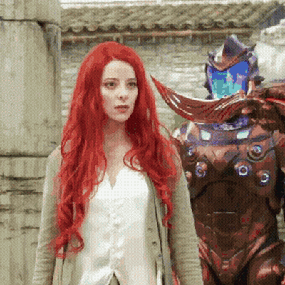 Woman With Long Red Hair Next To Robot GIF