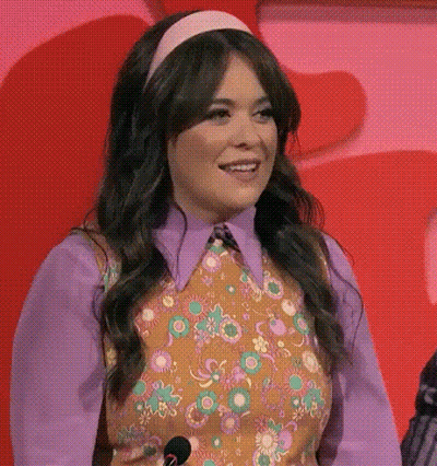 Woman With Microphone Purple Shirt Floral Vest Smiling GIF