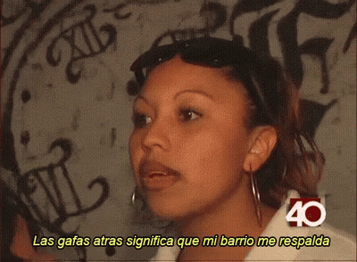 Woman With Mustache Wearing Sunglasses And Shirt Saying Las Gafas Atras Significa Que Mi Barrio Me Respald GIF