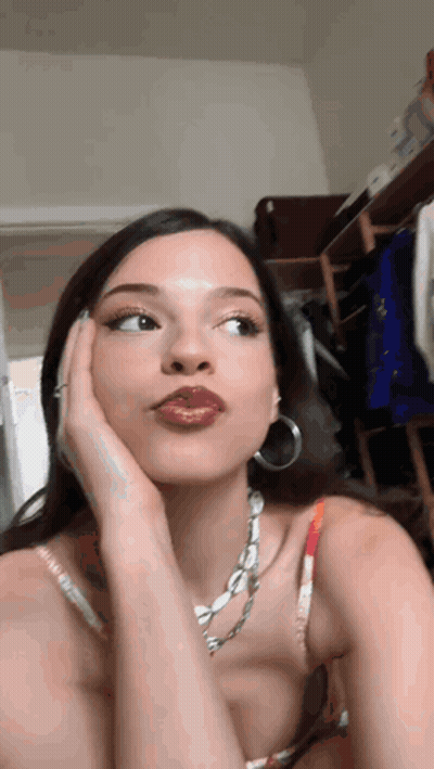 Woman With Necklace And Hoop Earrings Looking At Camera GIF