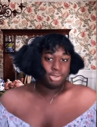 Woman With Necklace And Wig Before Floral Wallpaper GIF
