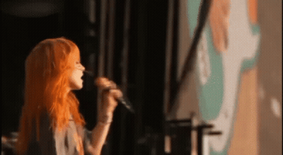 Woman With Orange Hair Singing Into Microphone GIF