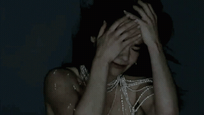 Woman With Pearl Necklace Holding Head In Pain GIF