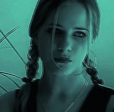 Woman With Pigtails And Hoop Earrings Looking At Camera In Dark Room GIF