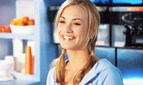 Woman With Pigtails Smiling In Front Of Blue Shelf GIF