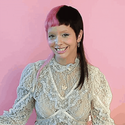 Woman With Pink And Black Hair Smiling In Lace Top GIF