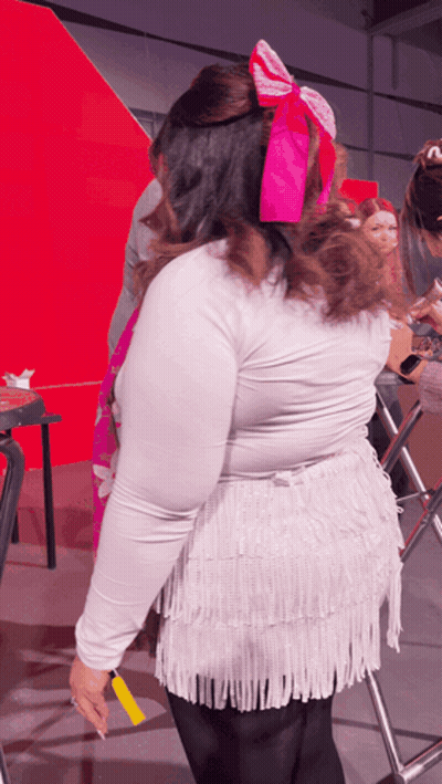 Woman With Pink Bow In Hair In Front Of Red Wall GIF