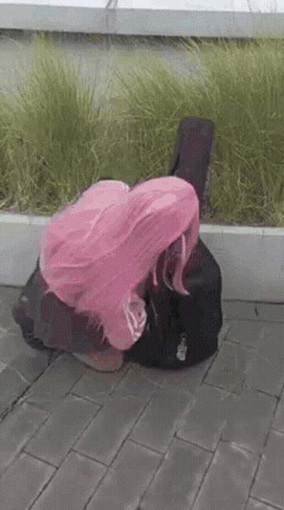 Woman With Pink Hair Kneeling Beside Guitar Case GIF