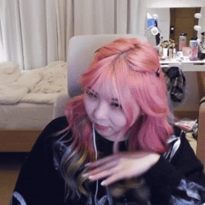 Woman With Pink Hair Sitting In Front Of Bed GIF