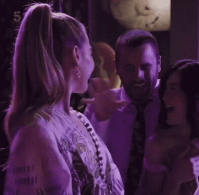 Woman With Ponytail Smiling Next To Man In Suit And Tie GIF