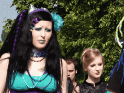 Woman With Purple Hair And Blue Makeup In Front Of Tree GIF