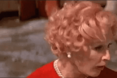 Woman With Red Curly Hair And Pearl Necklace Looking At Camera GIF