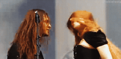 Woman With Red Hair And Man With Long Hair At Microphone GIF