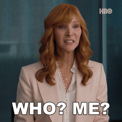 Woman With Red Hair And Pink Jacket Saying Who Me GIF
