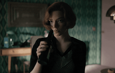 Woman With Red Hair Holding Bottle In Dark Room GIF