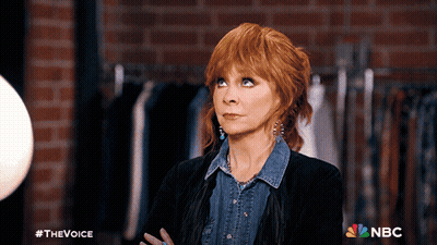 Woman With Red Hair In Front Of Brick Wall With NBC Logo GIF