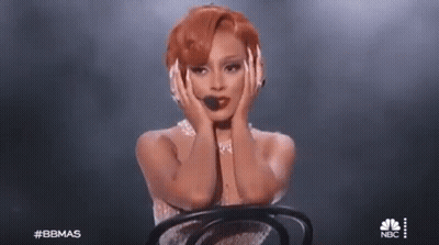 Woman With Red Hair Sitting In Chair On Stage GIF