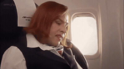 Woman With Red Hair Sitting On Airplane Eyes Closed GIF
