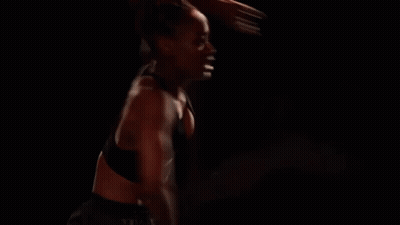 Woman With Red Hair Standing In Dark Room Arms Outstretched GIF
