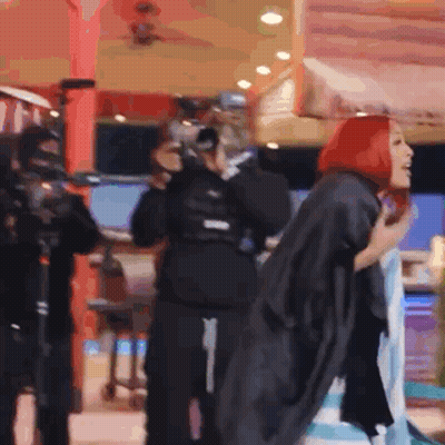 Woman With Red Hair Standing In Front Of Crowd GIF