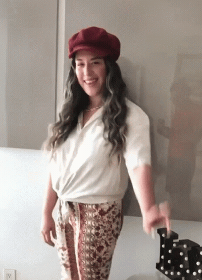 Woman With Red Hat And White Shirt Standing By Wall GIF