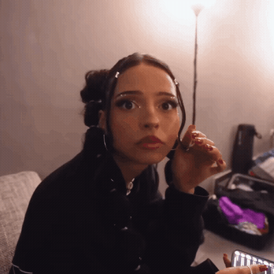 Woman With Red Nails Sitting On Couch Looking At Camera GIF