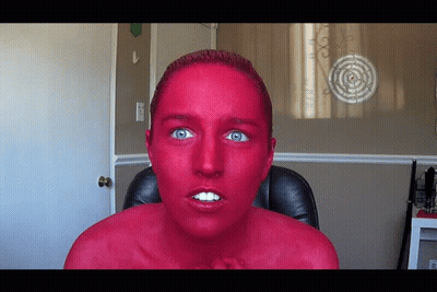 Woman With Red Paint Face Sitting Before Target GIF