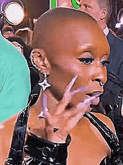 Woman With Shaved Head In Black Dress And Earrings GIF